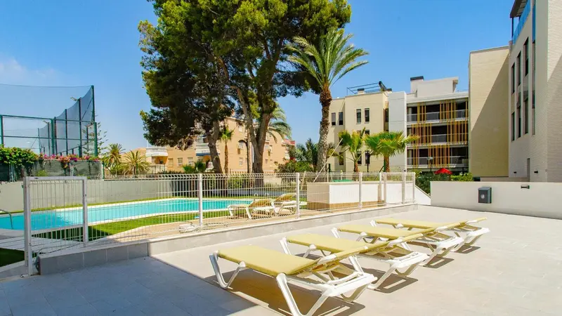 Transats alignés sur une terrasse ensoleillée près d'une piscine.