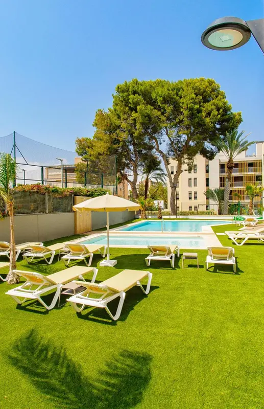 Transats alignés au bord d'une piscine ensoleillée, entourée de végétation luxuriante.
