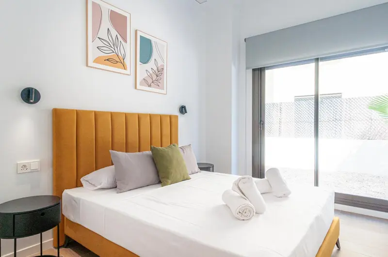 Une chambre lumineuse avec un grand lit et un accès à une terrasse.