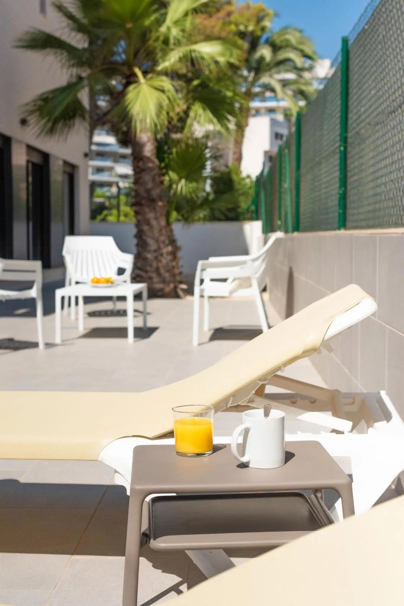 Transats et table basse avec boissons sur une terrasse ensoleillée.