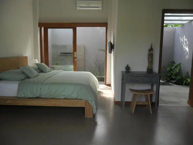 Une chambre lumineuse avec un grand lit et un accès à un espace extérieur.