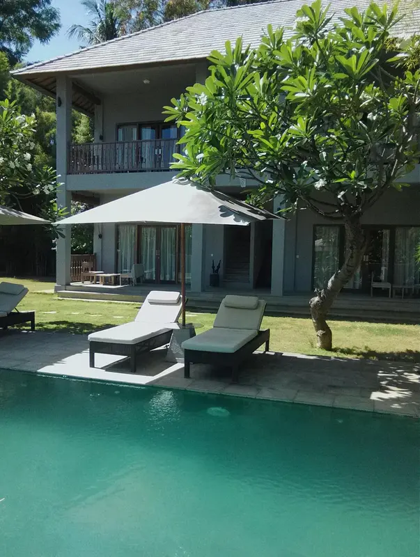 Deux transats invitent à la détente au bord d'une piscine turquoise, devant un bâtiment aux lignes épurées.