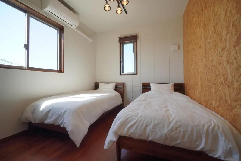 Une chambre lumineuse avec deux lits simples et un mur en bois.