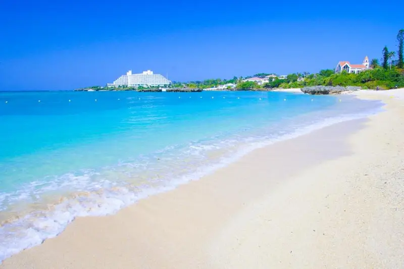 Plage de sable blanc bordée d'une eau turquoise et d'une végétation luxuriante.
