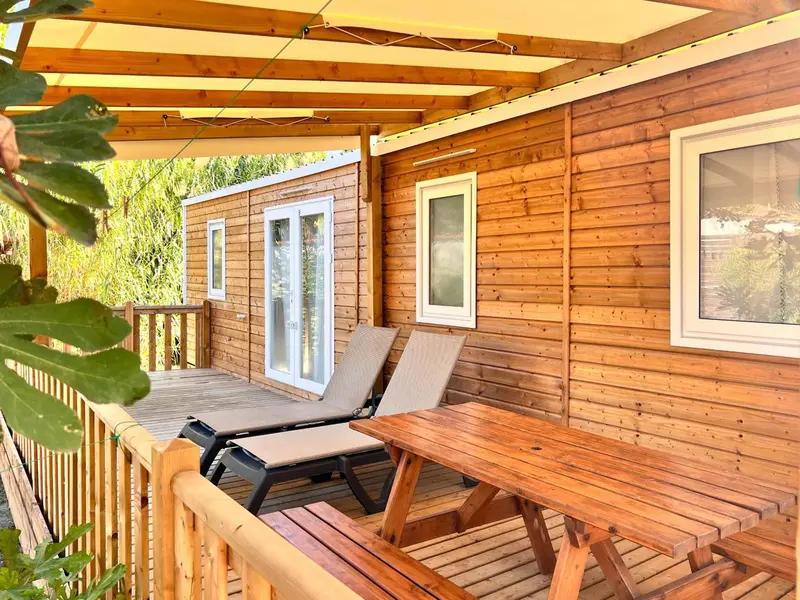 Terrasse en bois devant un chalet en bois clair.