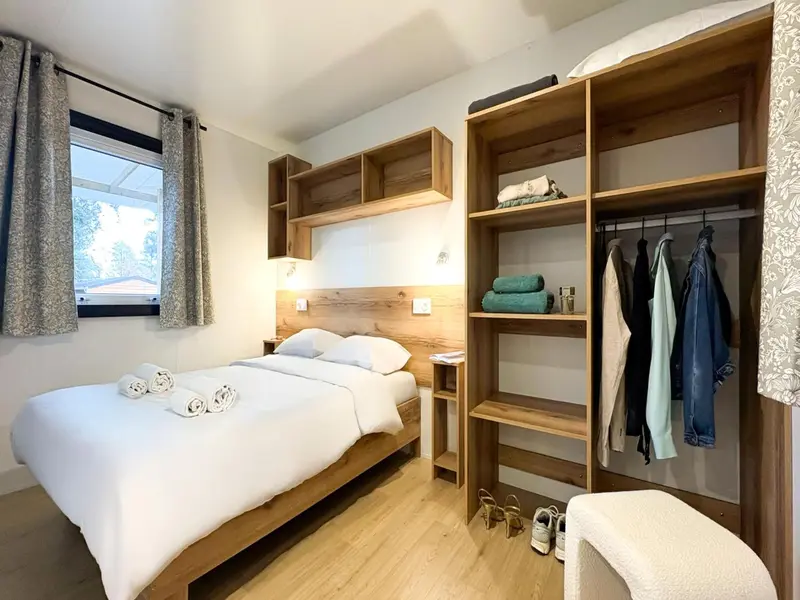 Une chambre lumineuse avec un lit double et un espace de rangement.