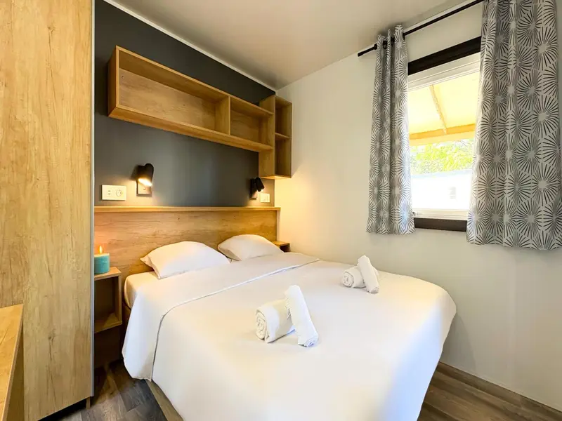 Une chambre lumineuse avec un lit double et une décoration sobre.