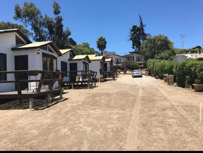 Vue d'ensemble d'une série de chalets individuels avec terrasse et parking en terre.