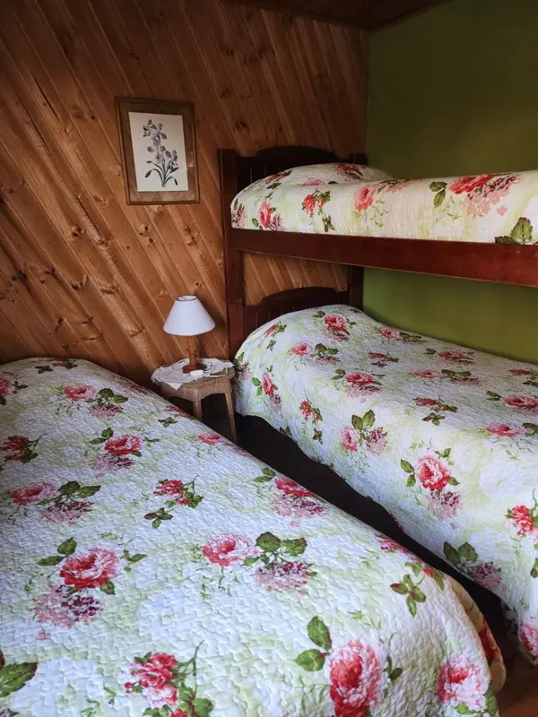 Une chambre avec deux lits superposés et un lit simple, recouverts de motifs floraux.