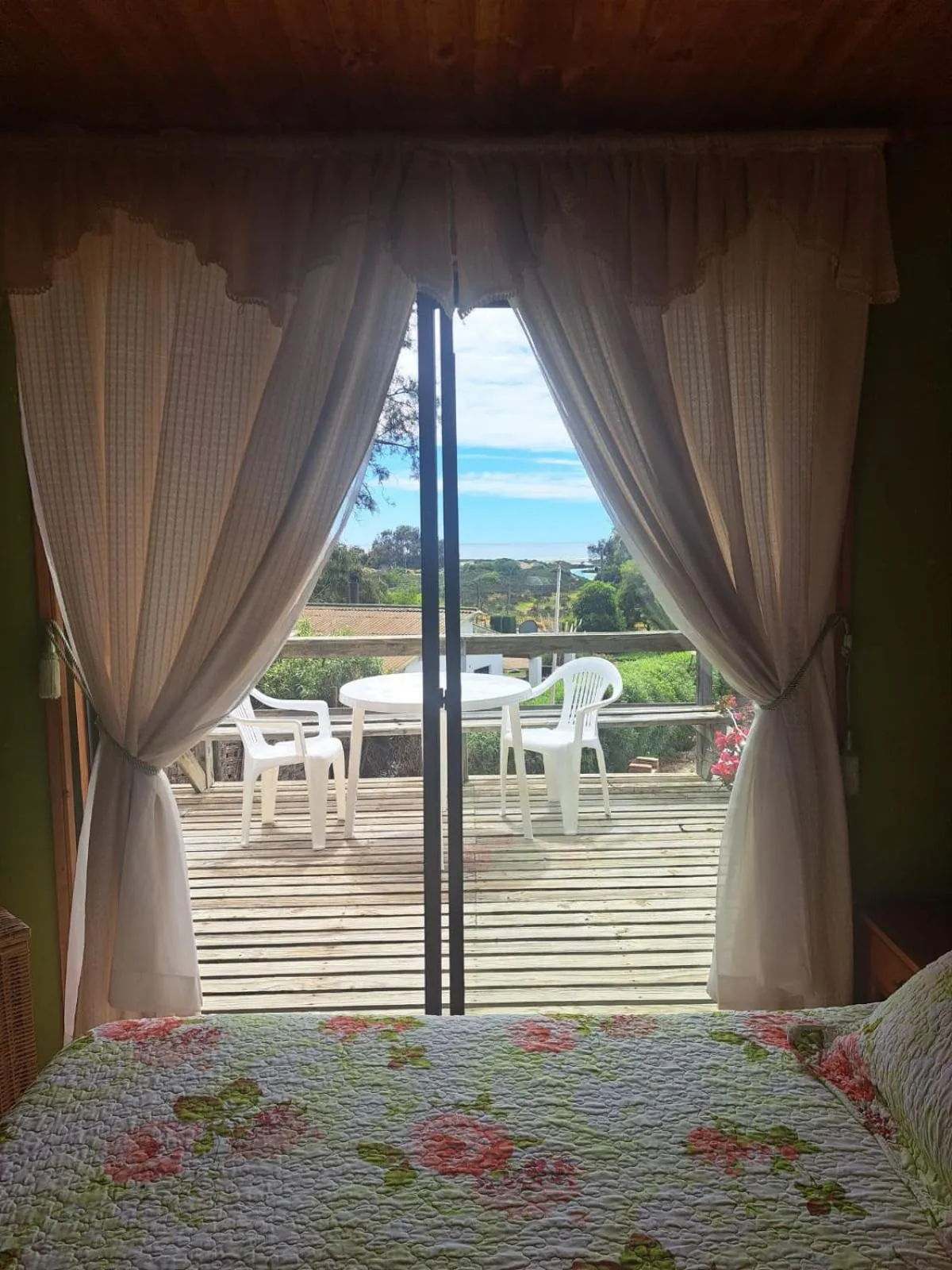 Vue sur une terrasse en bois depuis l'intérieur d'une pièce.
