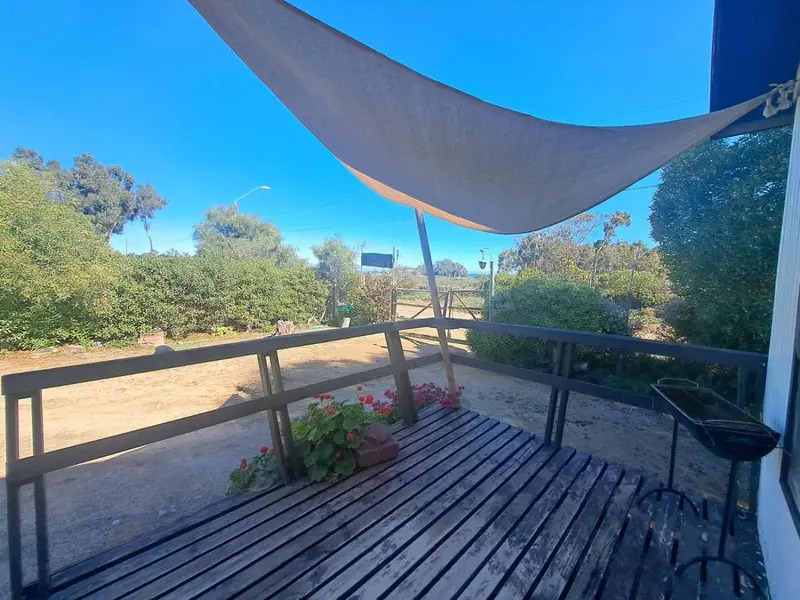 Terrasse ombragée avec garde-corps en bois et végétation.
