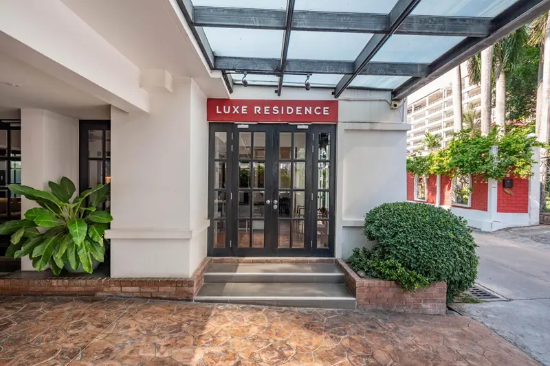 Entree d'une residence avec un auvent et des plantes vertes.