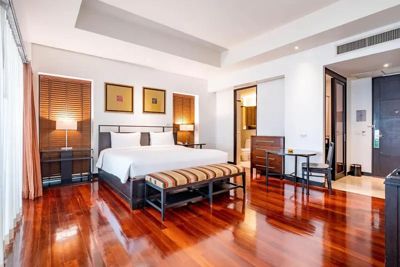 Une chambre spacieuse avec un grand lit et un banc au pied du lit.