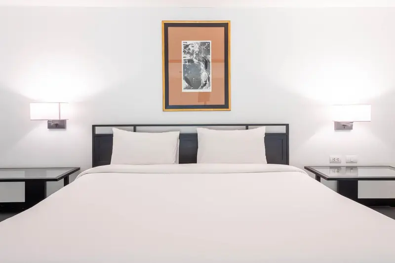 Une chambre avec un grand lit blanc et des tables de chevet.