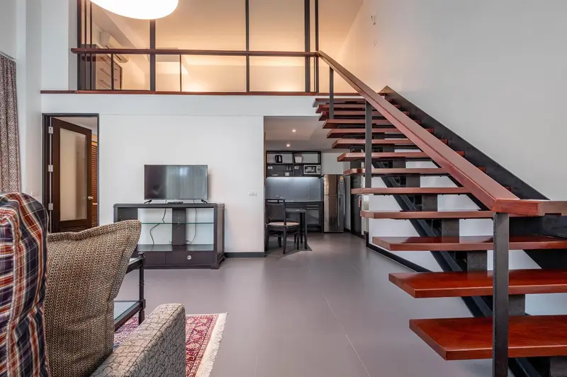 Espace de vie intérieur lumineux avec escalier en bois et canapé.