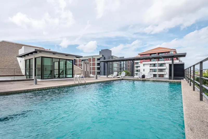 Piscine rectangulaire turquoise avec transats sur une terrasse ensoleillée.