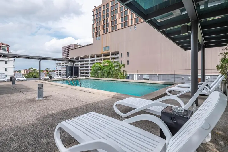 Transats blancs disposés autour d'une piscine rectangulaire sur un toit-terrasse.