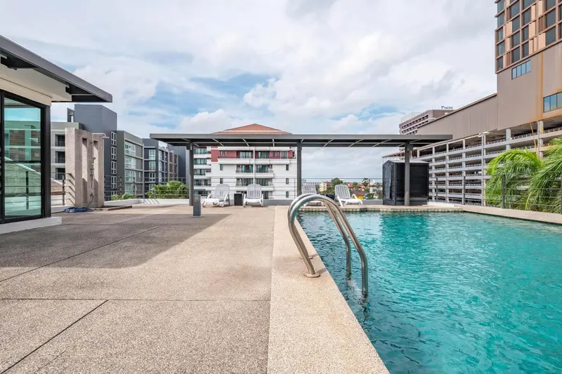 Une piscine rectangulaire avec des transats et un espace dallé.