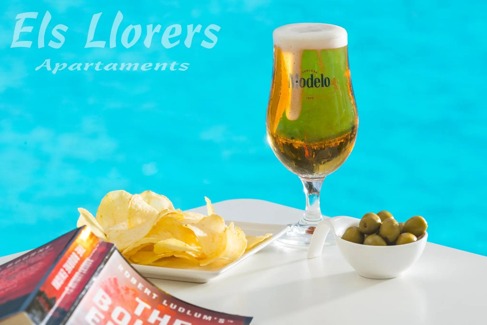 Un verre de bière et des collations sur une table au bord d'une piscine.