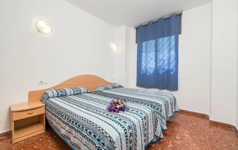 Une chambre lumineuse avec un lit recouvert d'une courtepointe décorative et une fenêtre.