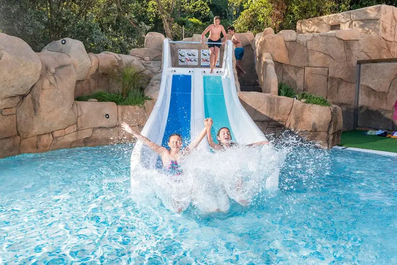 Des enfants s'amusent dans une piscine avec un toboggan aquatique.