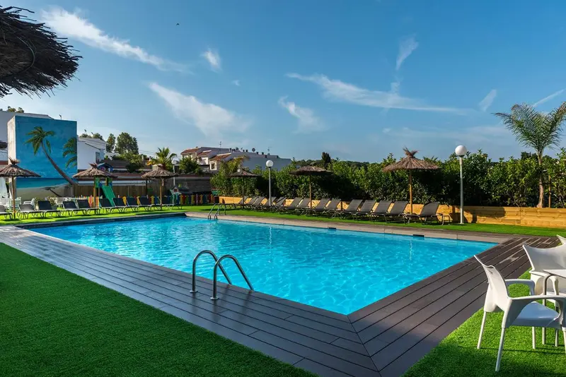 Une piscine rectangulaire bordée d'une terrasse en bois et de chaises longues.