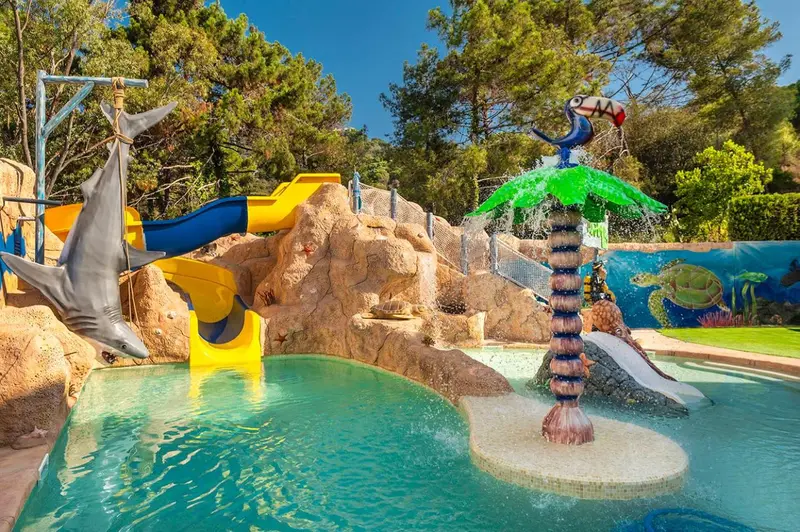 Toboggans aquatiques colorés se jettent dans une piscine décorée de sculptures marines.