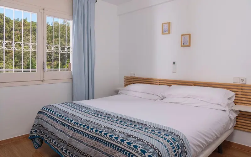 Une chambre lumineuse avec un grand lit recouvert d'une courtepointe.