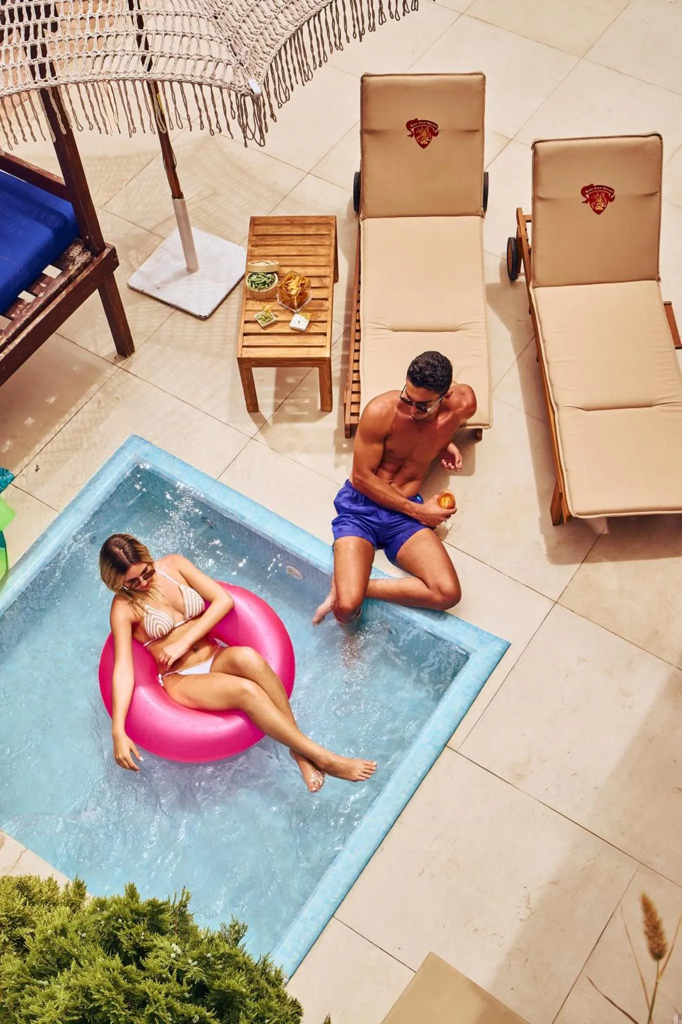 Deux personnes se détendent au bord d'une piscine ensoleillée.