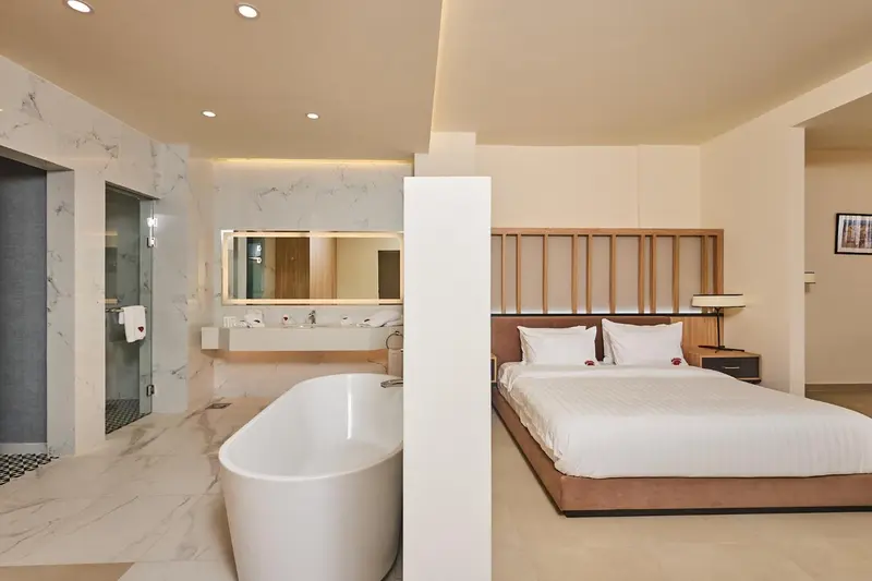 Une chambre lumineuse avec un grand lit et une baignoire.
