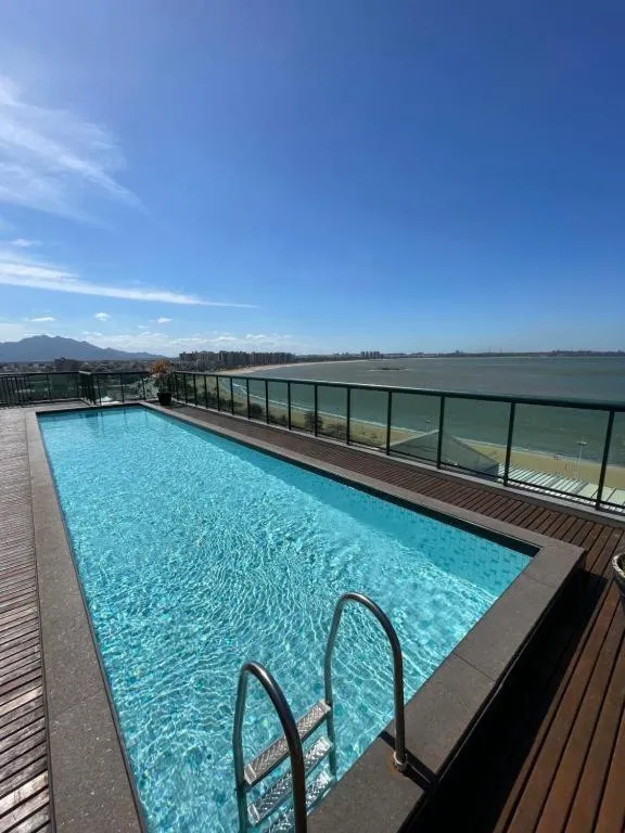 Piscine rectangulaire sur une terrasse avec vue sur la mer et les montagnes.