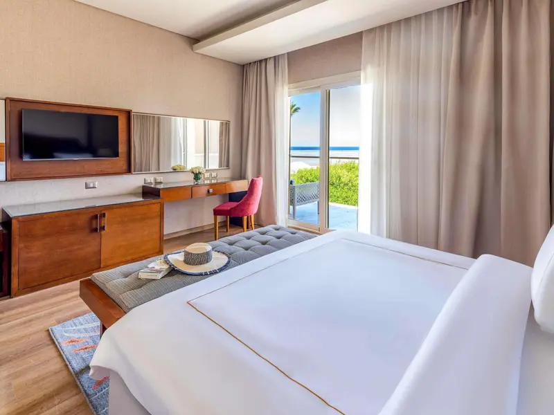 Chambre lumineuse avec un lit confortable et vue sur la mer.