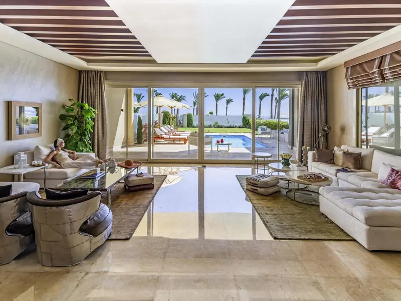 Espace de vie lumineux avec canapés et vue sur une piscine et une plage.