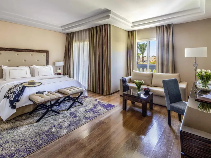 Une chambre lumineuse avec un grand lit et un coin salon.