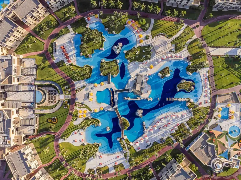 Vue aérienne d'un complexe hôtelier avec des piscines en forme d'animaux marins et des espaces verts.
