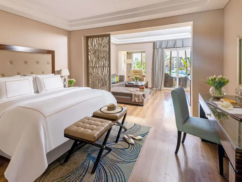 Une chambre lumineuse avec un grand lit et un espace salon.