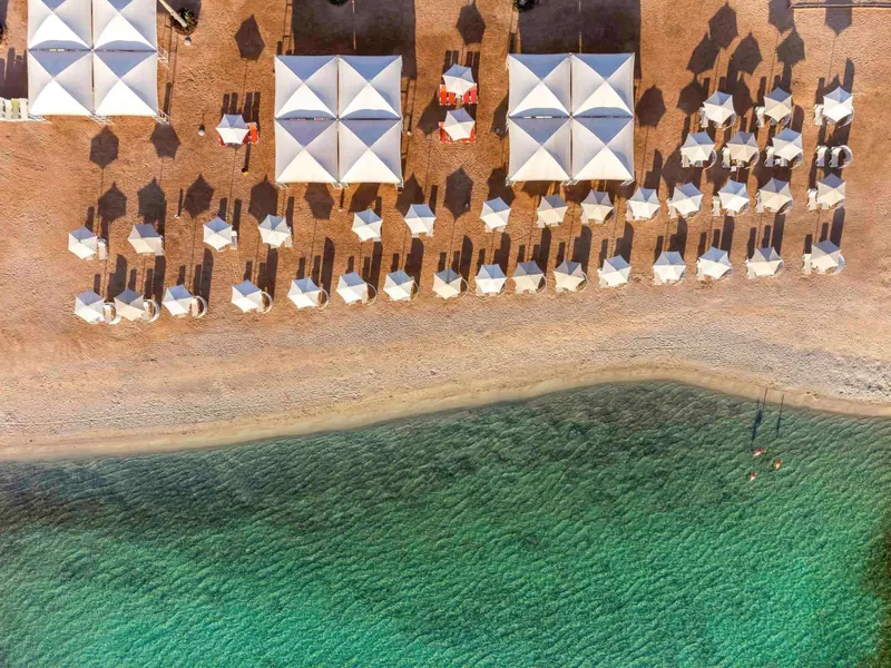 Vue aérienne d'une plage de sable avec des parasols et des transats.