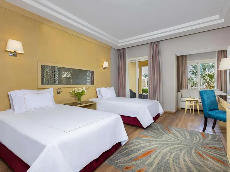 Chambre lumineuse avec deux lits simples et une décoration florale.