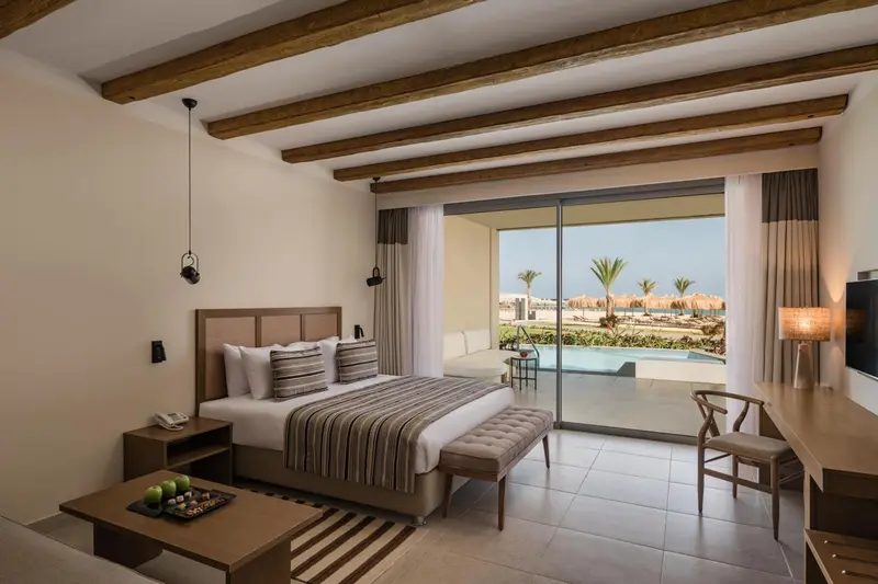 Une chambre lumineuse avec un grand lit et un accès à une terrasse avec vue sur la mer.