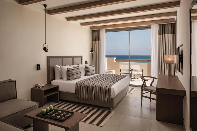 Une chambre lumineuse avec un grand lit et un accès à une terrasse vue sur mer.