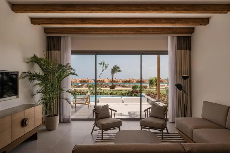 Espace de détente intérieur avec vue sur une piscine et la mer.