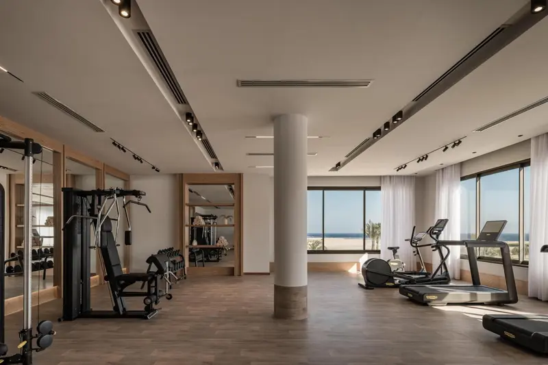 Une salle de sport lumineuse avec des équipements de musculation et une vue sur la mer.
