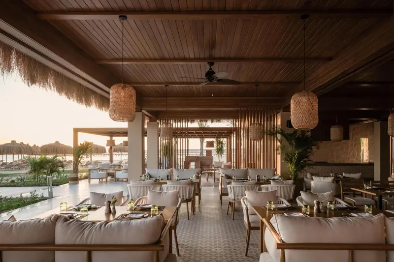 Une salle à manger extérieure avec des tables dressées et un plafond en bois.
