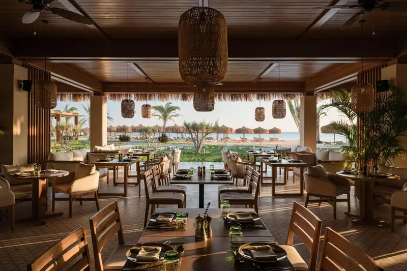 Une salle à manger extérieure avec des tables dressées face à la mer.