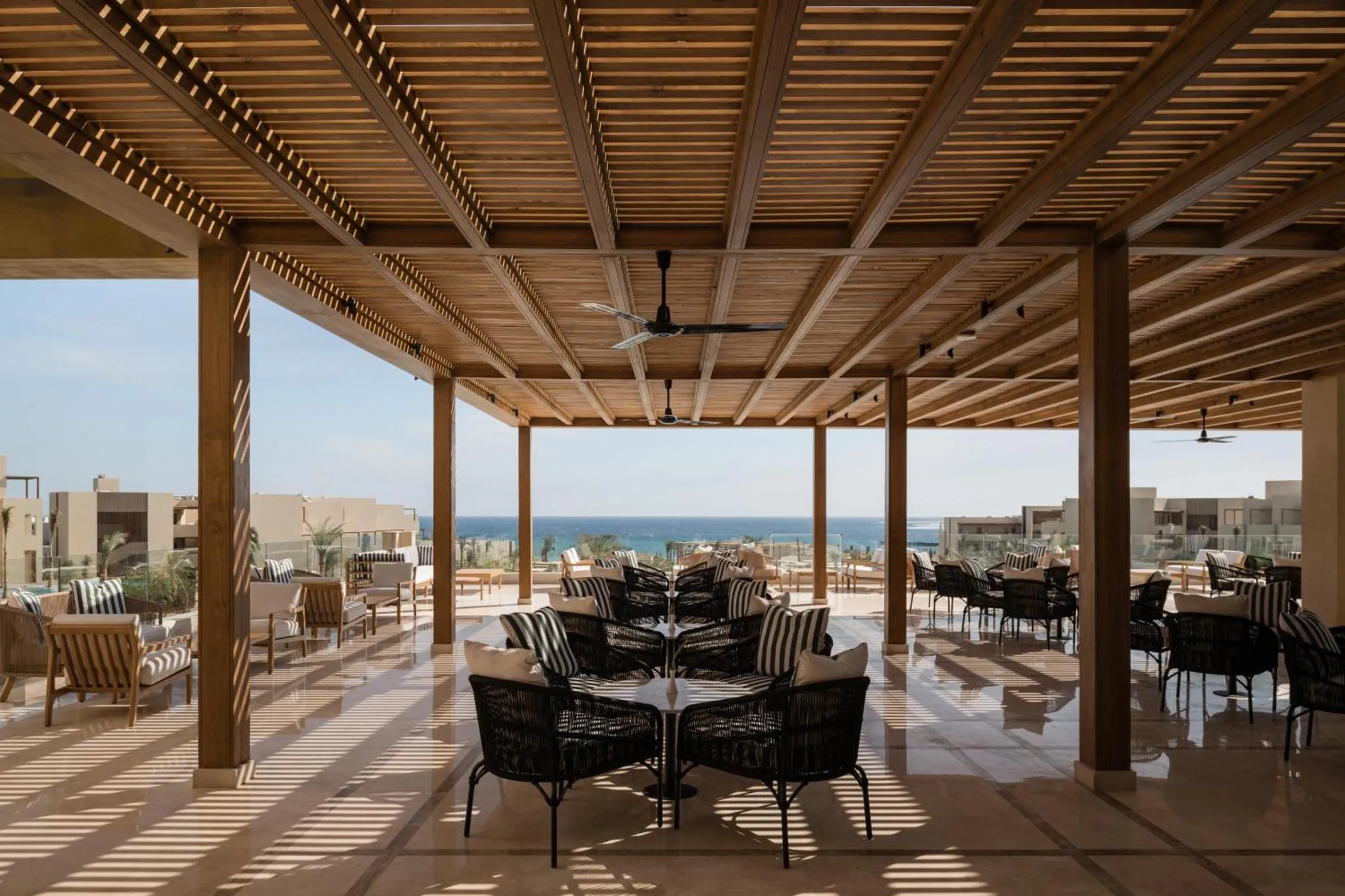 Terrasse ombragée avec mobilier de détente et vue sur la mer.