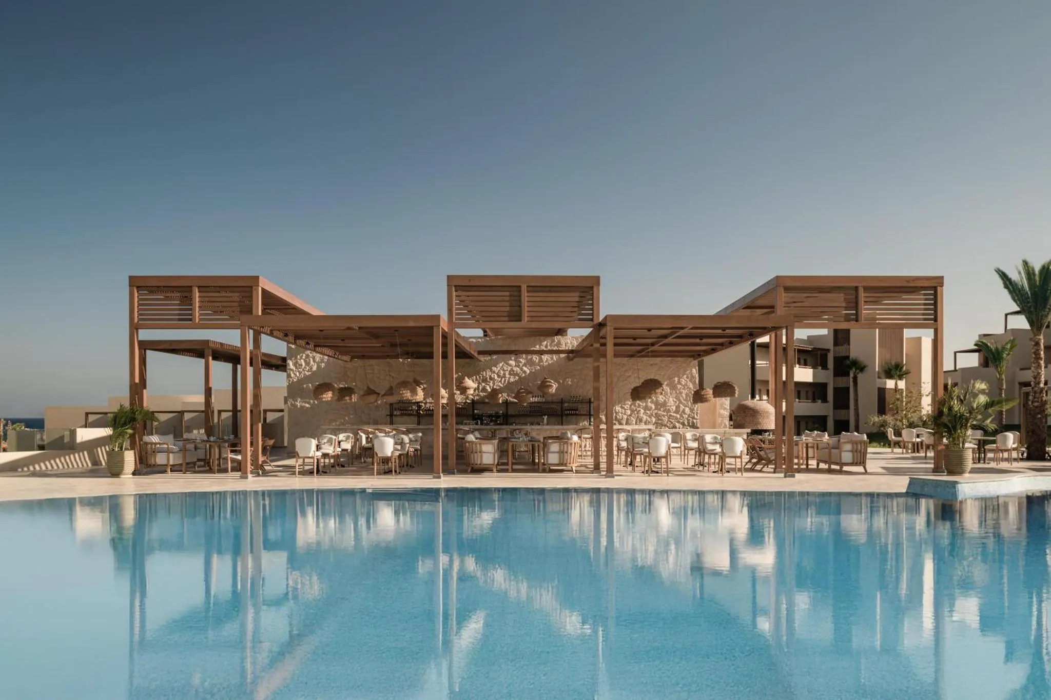 Terrasse ombragée avec mobilier de détente au bord d'une piscine turquoise.