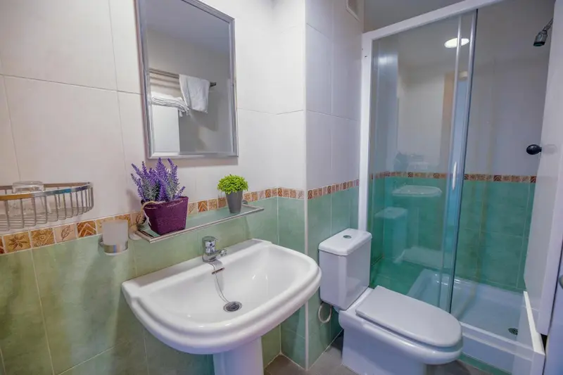 Une salle de bain claire avec douche et lavabo.
