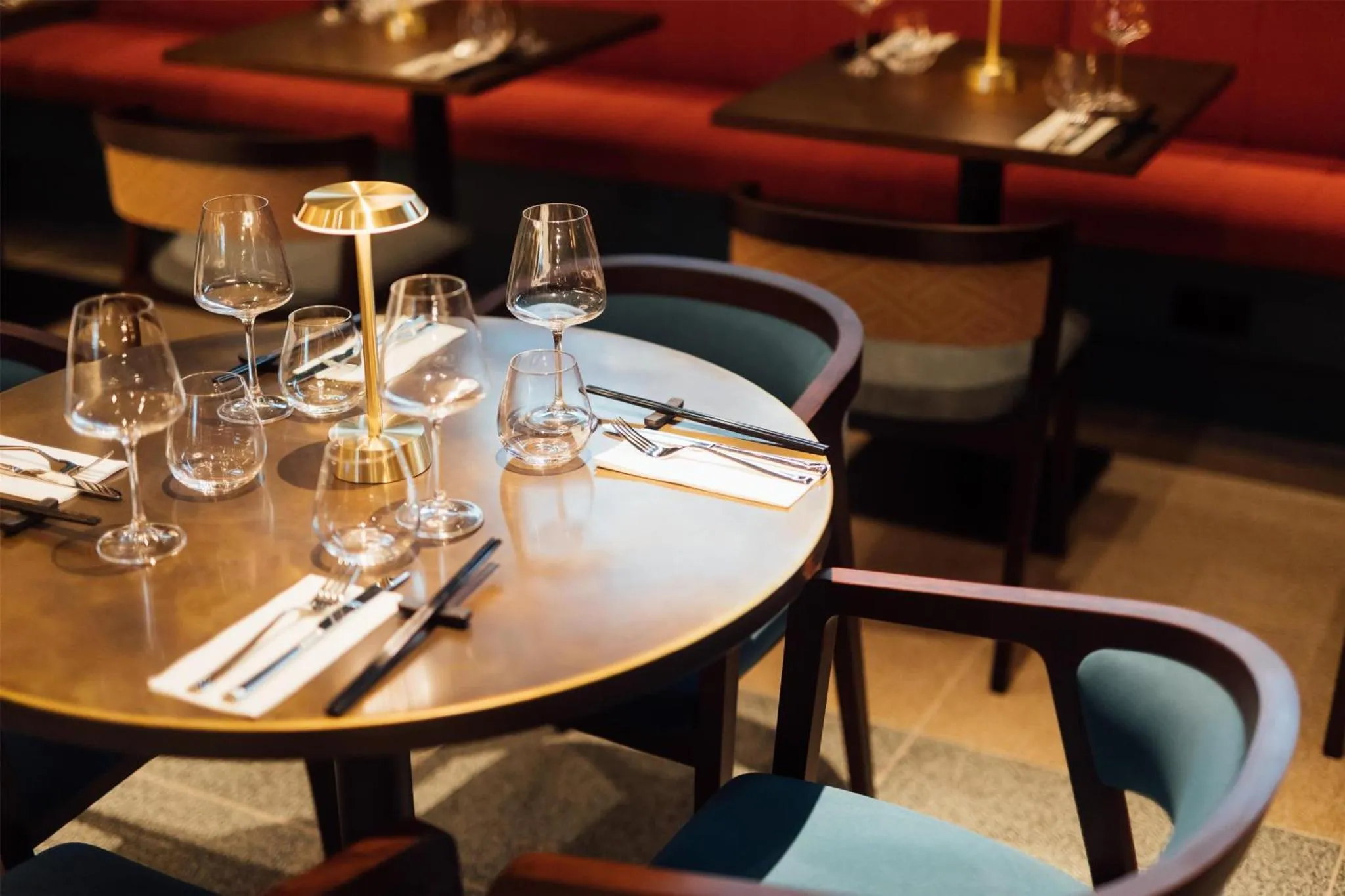 Tables rondes dressées avec couverts et verres dans une salle de restaurant.