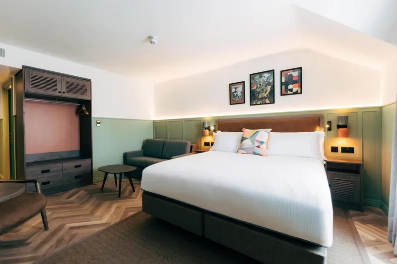 Une chambre lumineuse avec un lit double et un canapé vert.