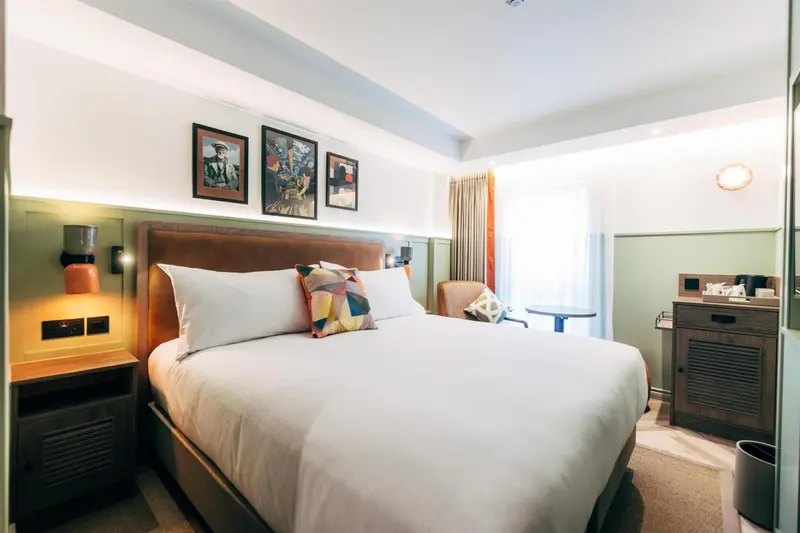 Une chambre lumineuse avec un grand lit et des tableaux décoratifs.
